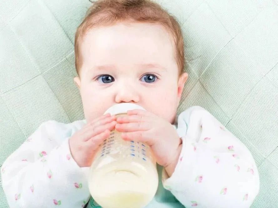 A baby is holding the bottle and drinking milk