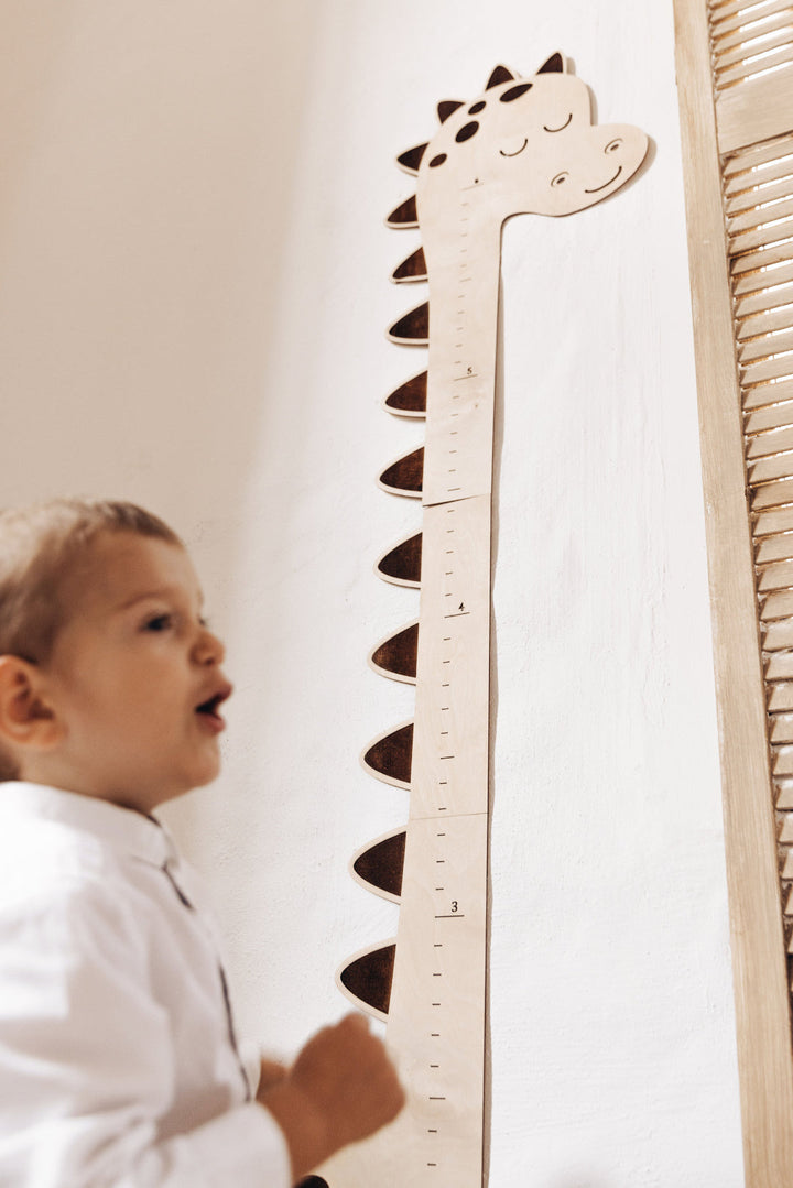 Little boy is using a dinosaur growth chart height ruler - 2