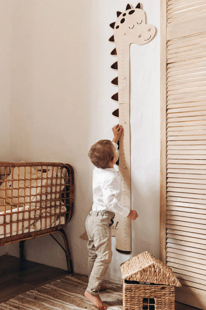 Little boy is using a dinosaur growth chart height ruler